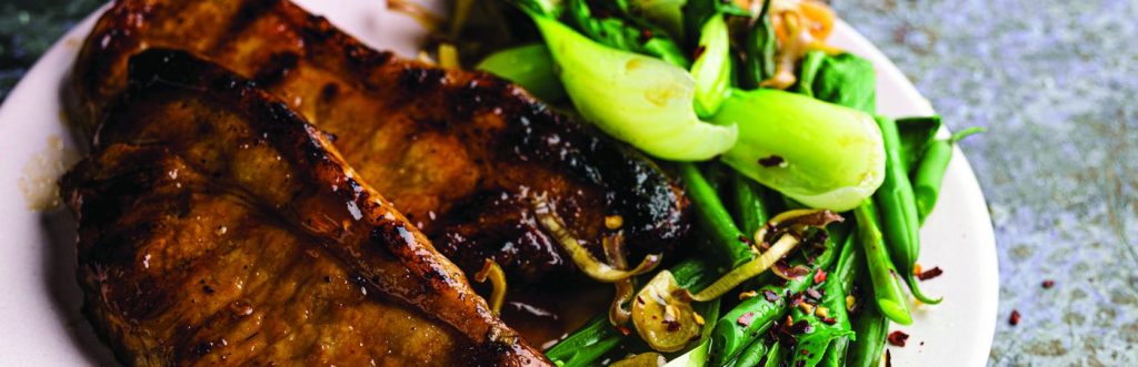 Grilled meat and greens on a plate.